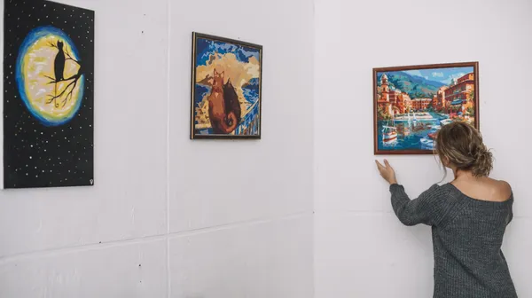 1778852887-woman-placing-picture-wall (1)